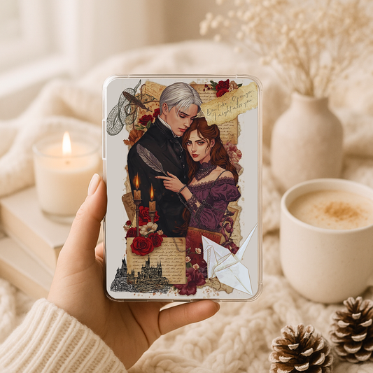 Dark romance gothic couple artwork inside a clear Kindle case, photographed in a cozy neutral setting with a candle, coffee cup, soft textures, and romantic vintage collage details
