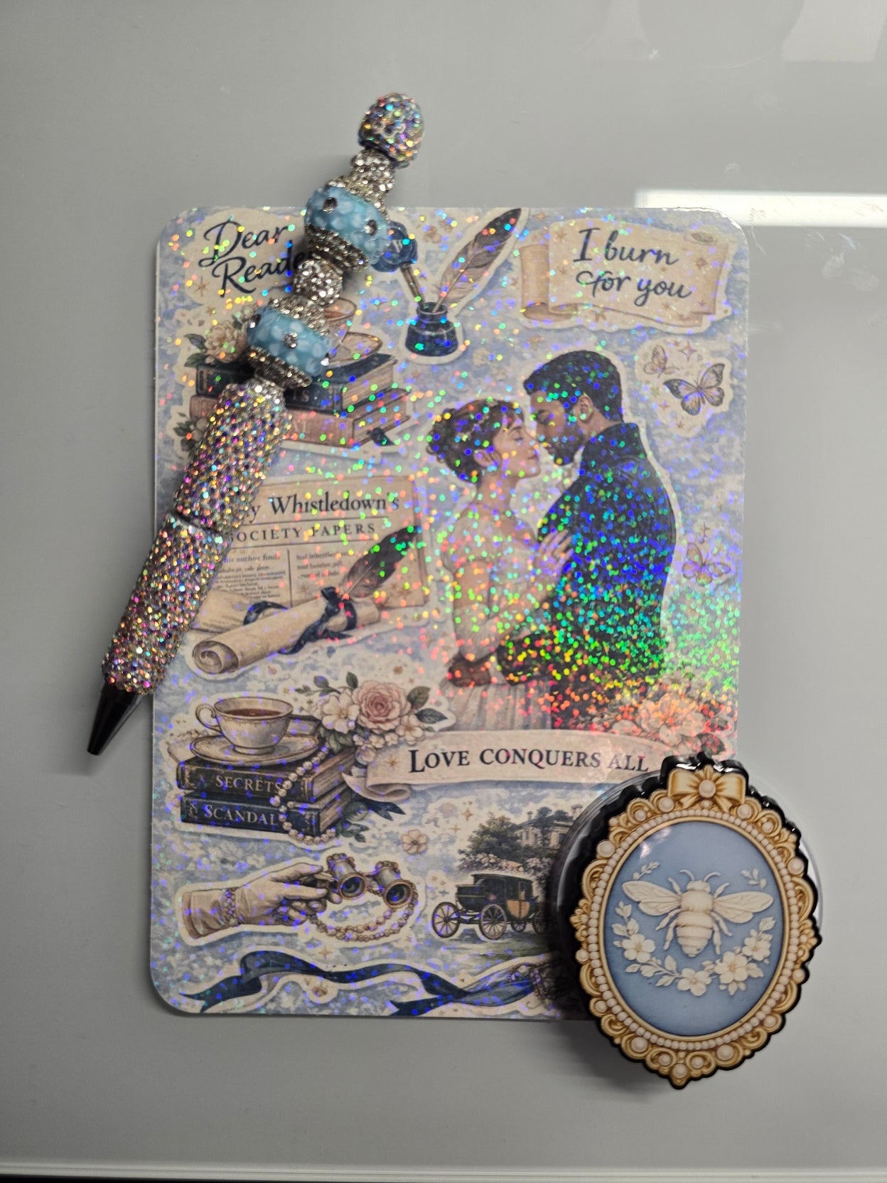 Close-up sparkle of holographic blue Kindle insert with romance reader vintage collage aesthetic

