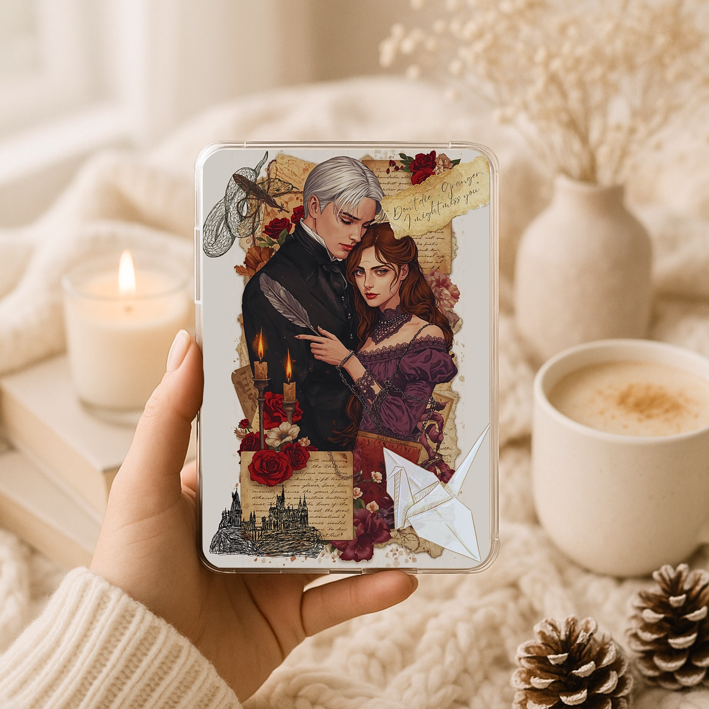 Dark romance gothic couple artwork inside a clear Kindle case, photographed in a cozy neutral setting with a candle, coffee cup, soft textures, and romantic vintage collage details