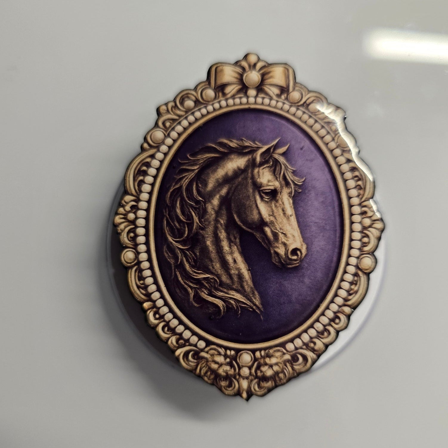 Regency inspired horse cameo magnetic Kindle grip with ornate gold frame and plum background

