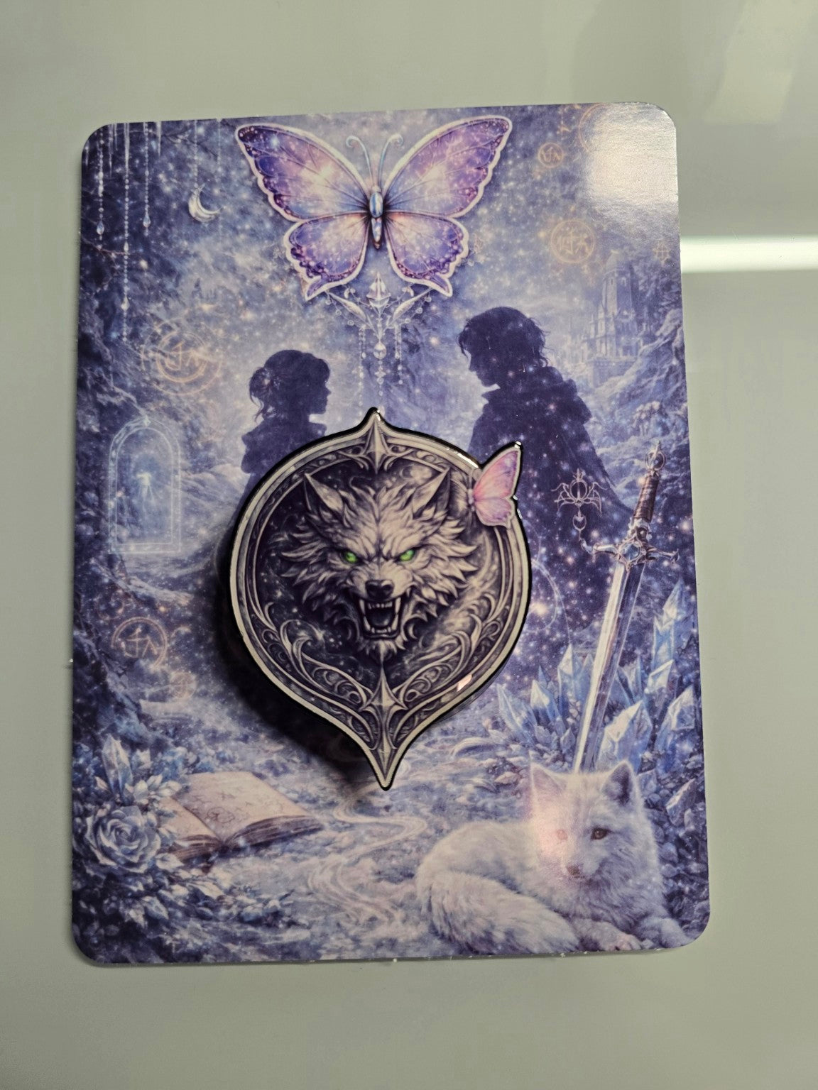 Matching fantasy romance MagSafe grip featuring detailed silver wolf design with glowing green eyes